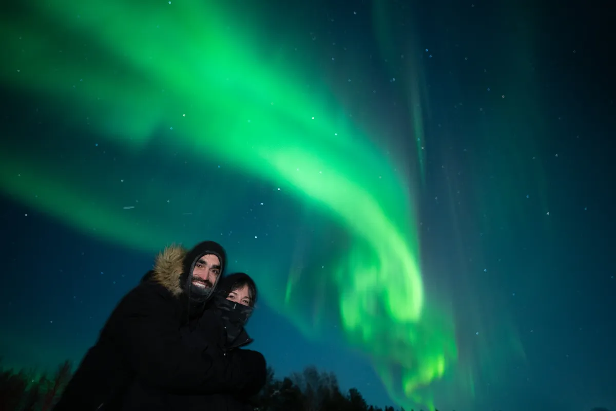 Guests under a green aurora arc on an Experience Tours hunt near Rovaniemi